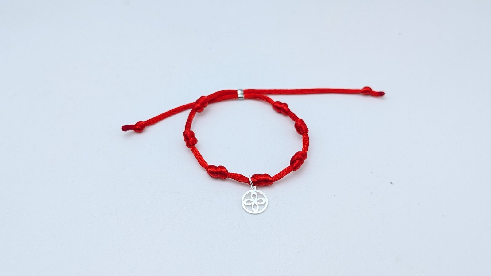 Pulsera roja de siete nudos con colgante plateado